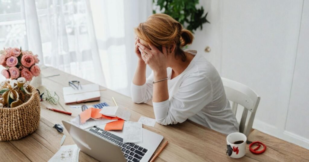 Mujer agotada frente al ordenador por bloqueo económico y trauma transgeneracional